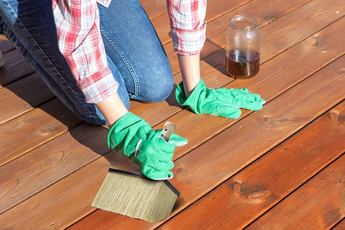 Person ölt Holzboden mit Pinsel